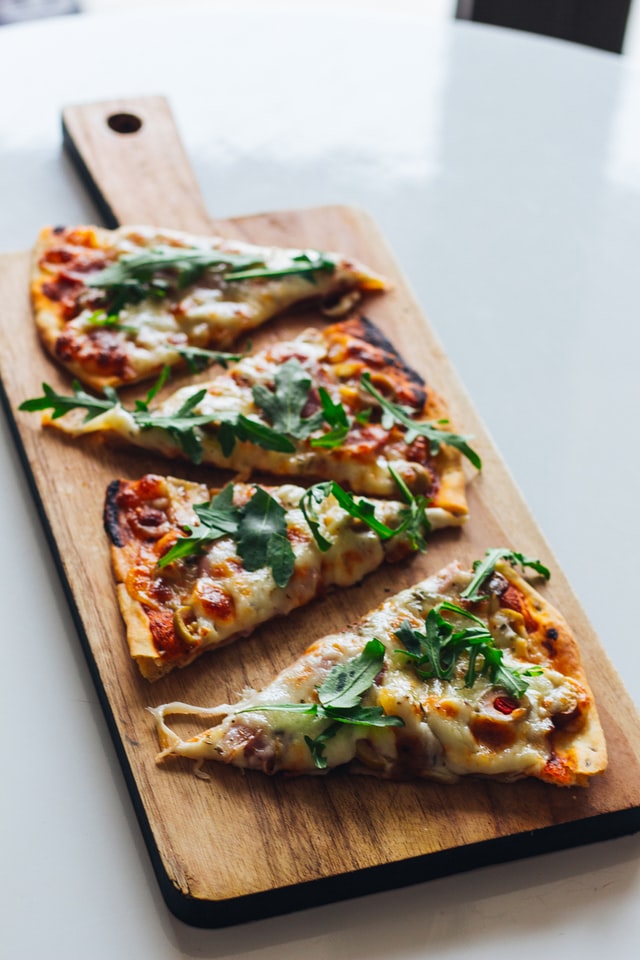 four slices of pizza being served on a wood board